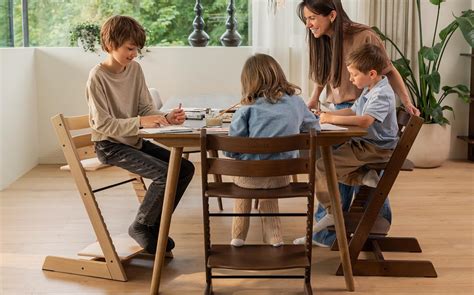 Famiglia che mangia intorno a un tavolo con bambini seduti su sedie Stokke Tripp Trapp