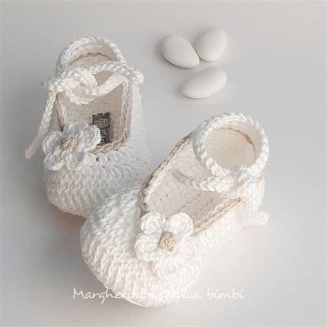 primo piano di scarpine battesimo realizzate all'uncinetto con filato bianco e dettagli in raso