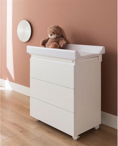 Bambino sorridente sdraiato su un fasciatoio bianco con ripiani sottostanti