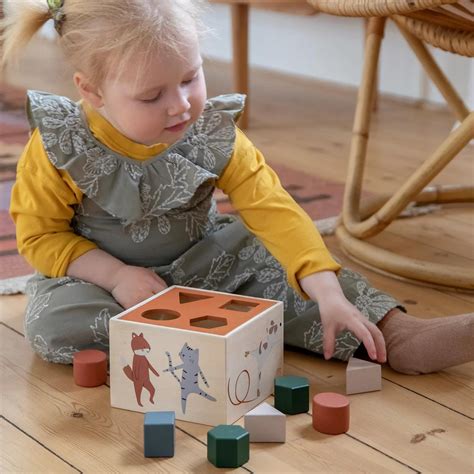 bambino che esplora un cubo di legno con forme geometriche