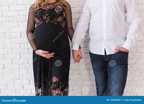 Coppia incinta si tiene la mano sorridendo