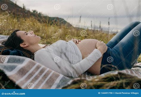 Donna incinta accarezza il suo pancione in modo rilassato