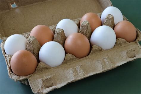 Una cesta di uova fresche di diversa colorazione su un piano di legno