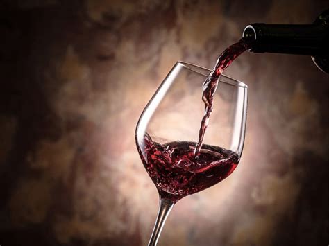 Calice di vino rosso con paesaggio collinare sullo sfondo