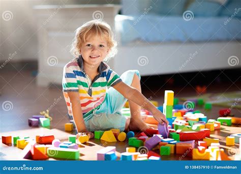 bambino che gioca con costruzioni in legno sul tappeto