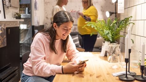 Una mamma felice che utilizza uno smartphone per fare shopping online in un ambiente confortevole