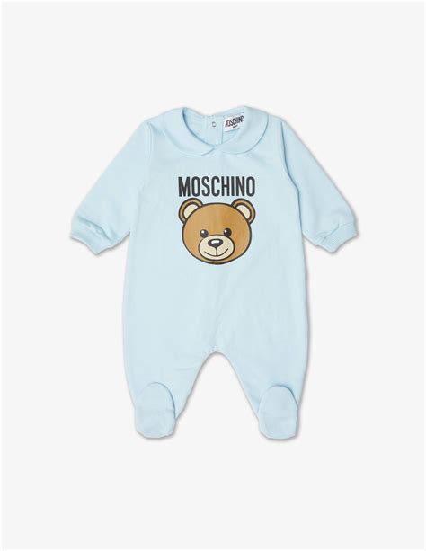 Una tutina Moschino modello pagliaccetto in colore celeste con colletto bianco e logo orsetto in evidenza