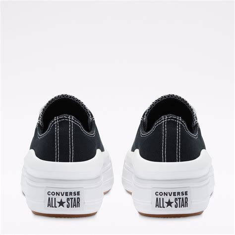 Dettaglio di scarpe Converse accostate a pantaloni di tessuto nero