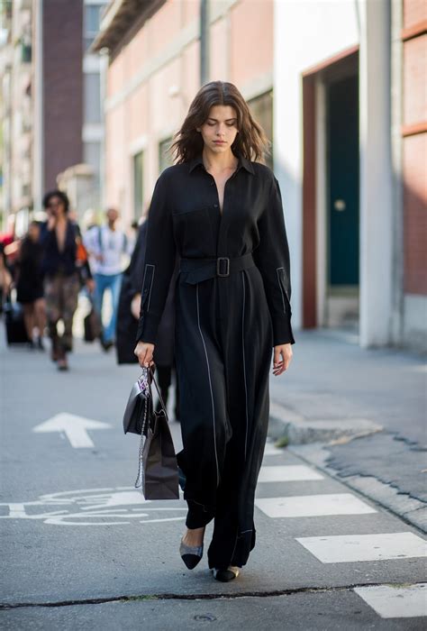 Modella che indossa una tuta nera elegante abbinata a sneakers classiche