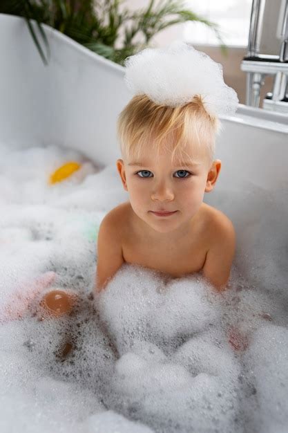bambino che gioca con pesciolini colorati nella vasca da bagno