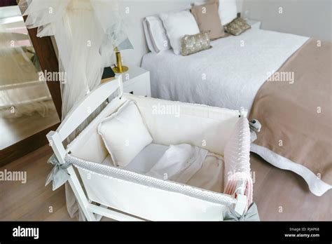 immagine di una culla fianco letto accanto al letto matrimoniale