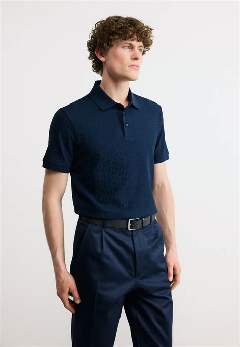 bambino che indossa una polo BOSS blu ozono in un ambiente marittimo