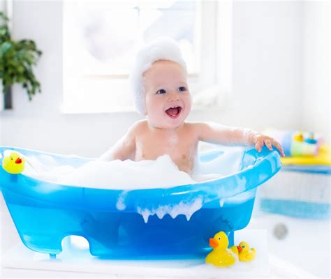 bambino che fa il bagnetto in una vaschetta con giochini