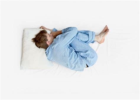 persona che dorme in posizione fetale in un letto confortevole