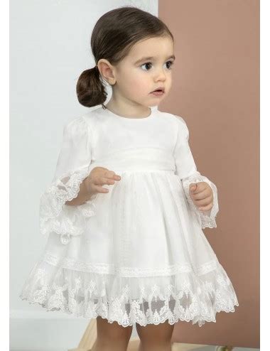 Bambina con vestito da battesimo bianco e ricamato