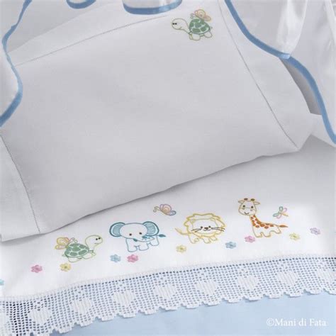 Dettaglio di un lenzuolino per culla in cotone bianco con rifiniture in pizzo ricamato