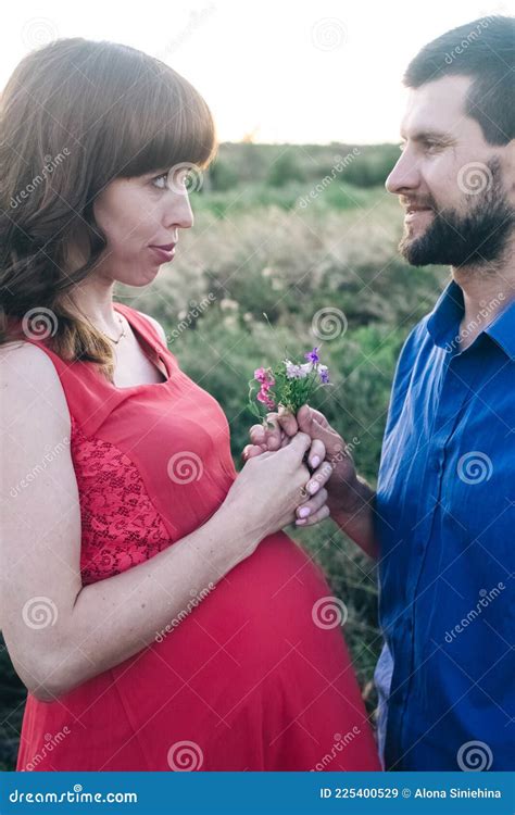 una donna incinta che guarda il tramonto in un campo di fiori
