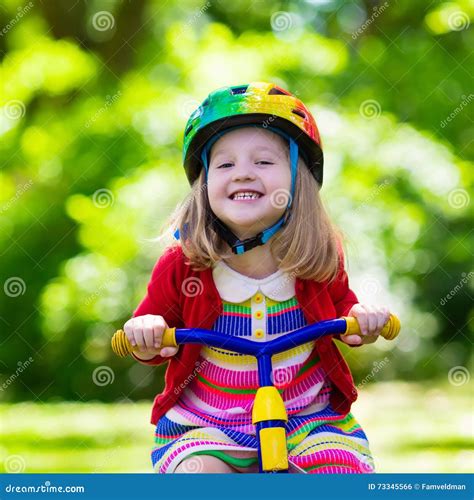bambina felice che gioca con un triciclo colorato in un parco soleggiato