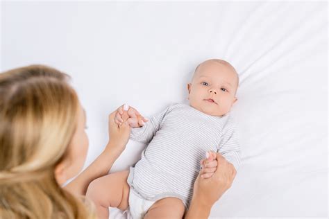 Un neonato sorride tenendo in mano un piccolo body Prénatal