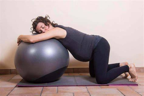 donna che utilizza la fitball durante il travaglio per esercizi di rotazione del bacino