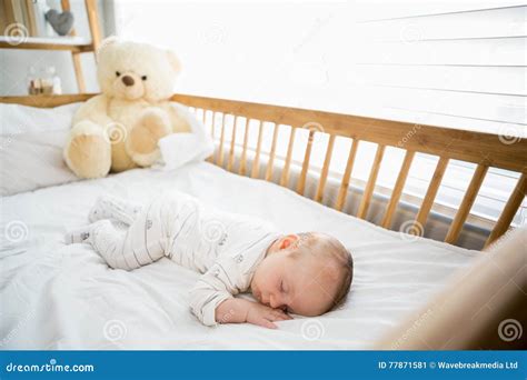 Immagine di un neonato che dorme serenamente in una culla con un piccolo dispositivo di rumore bianco nelle vicinanze