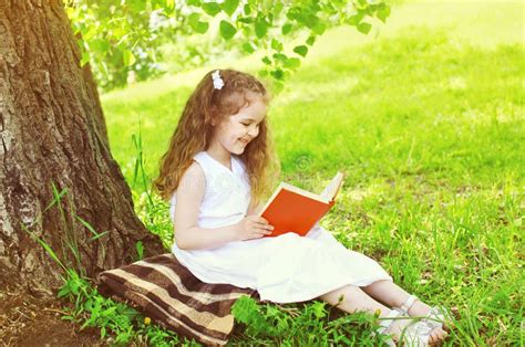 bambino che legge un libro di poesie all'ombra di un albero