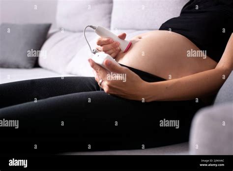 Una futura mamma che utilizza un doppler fetale sul pancione in un ambiente domestico confortevole