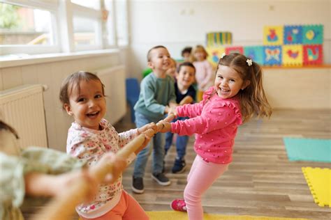 Bambini che interagiscono tra loro usando bambole e accessori in un contesto di asilo o ludoteca