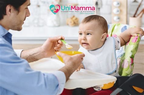 Bambino sorridente che mangia la pappa con un bavaglino con tasca