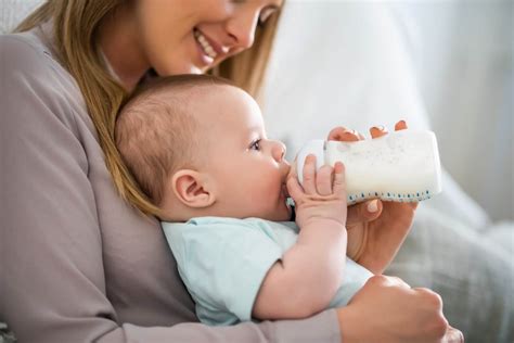 Bambino al seno e biberon a confronto con un cucchiaino