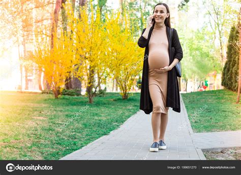 Pregnant woman walking in a park, suitable for third trimester