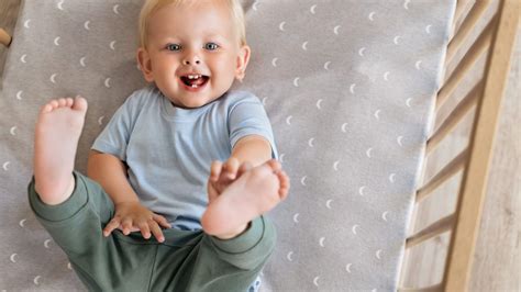 Bambino in tutina leggera che dorme serenamente in un lettino illuminato da una luce naturale primaverile