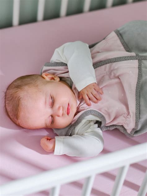 Un bebè dorme in un sacco nanna leggero all'interno di un lettino primaverile