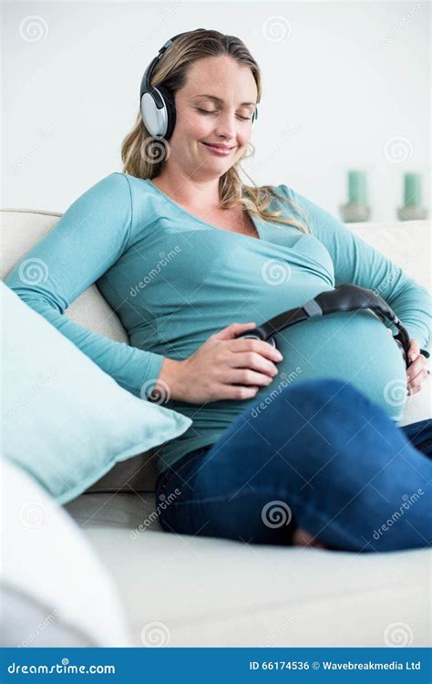 Donna incinta che ascolta musica con cuffie sulla pancia