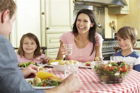 Famiglia che pranza insieme con il bambino al seggiolone a tavola