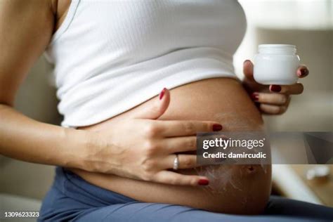 Donna incinta che si applica la crema solare sulla pancia