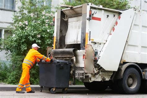 Operatore ecologico che raccoglie rifiuti in un contesto urbano residenziale a Lucca