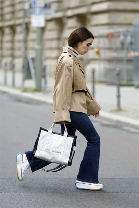Modella dodicenne che indossa jeans a zampa con sneakers bianche e t-shirt colorata in un ambiente urbano moderno
