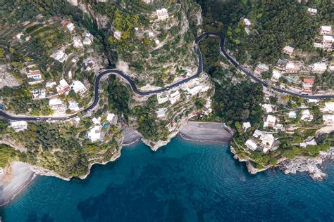 Veduta di una strada costiera salentina circondata da muretti a secco e vegetazione mediterranea