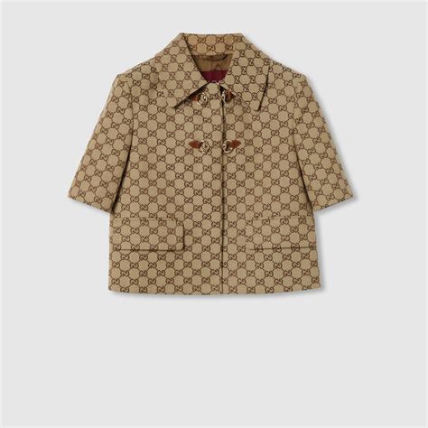 Modella bambina che indossa una gonna Gucci in tessuto GG con sfondo di un atelier di sartoria