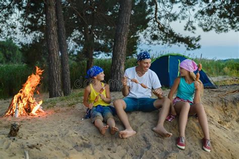 Famiglia che arrostisce salsicce su un falò pubblico