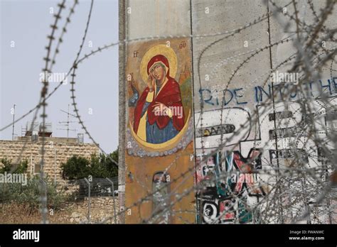 Muro di separazione a Betlemme con graffiti e filo spinato