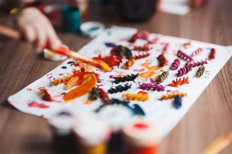 bambini che realizzano collage con pasta colorata
