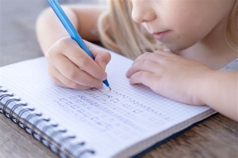 Un bambino che scrive su un quaderno con matite colorate, circondato da simboli grafici di lettere