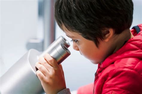 Bambino osserva al microscopio con stupore