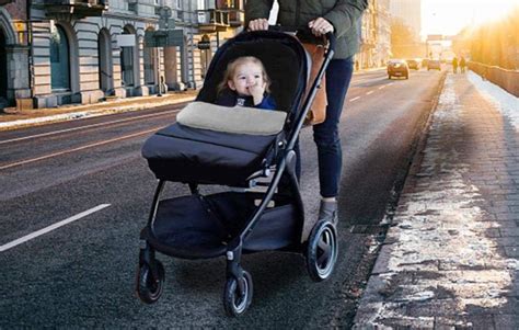 Una mamma con un passeggino trio in un contesto urbano