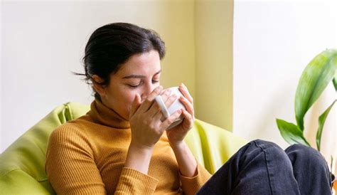 Donna in gravidanza che sorseggia una tisana calda in un ambiente rilassante