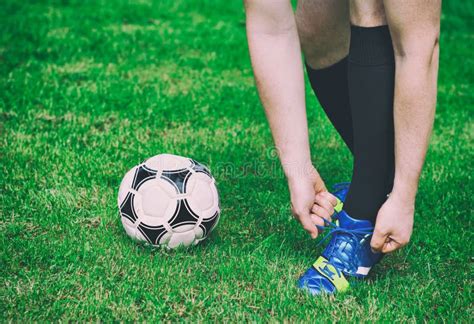ragazzo giovane calciatore che allaccia le scarpe da calcio su un campo in erba