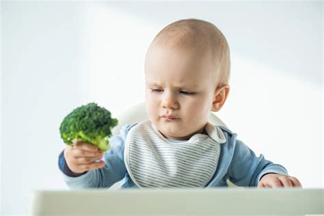Un bambino piccolo seduto a tavola che osserva i compagni mangiare