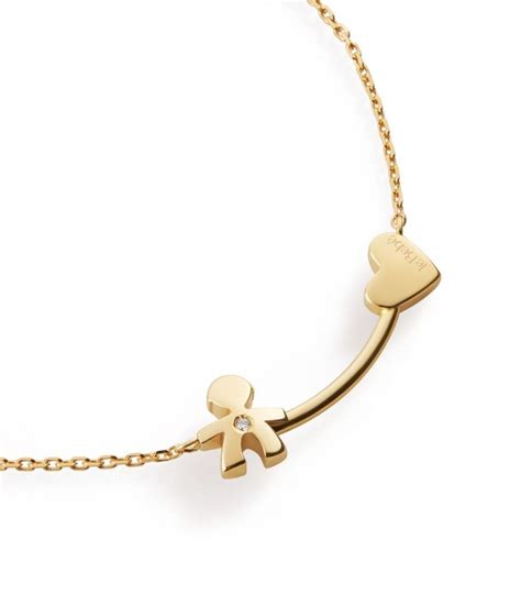 Una collana Le Bebè in oro con sagoma di bimbi posata su un piano elegante